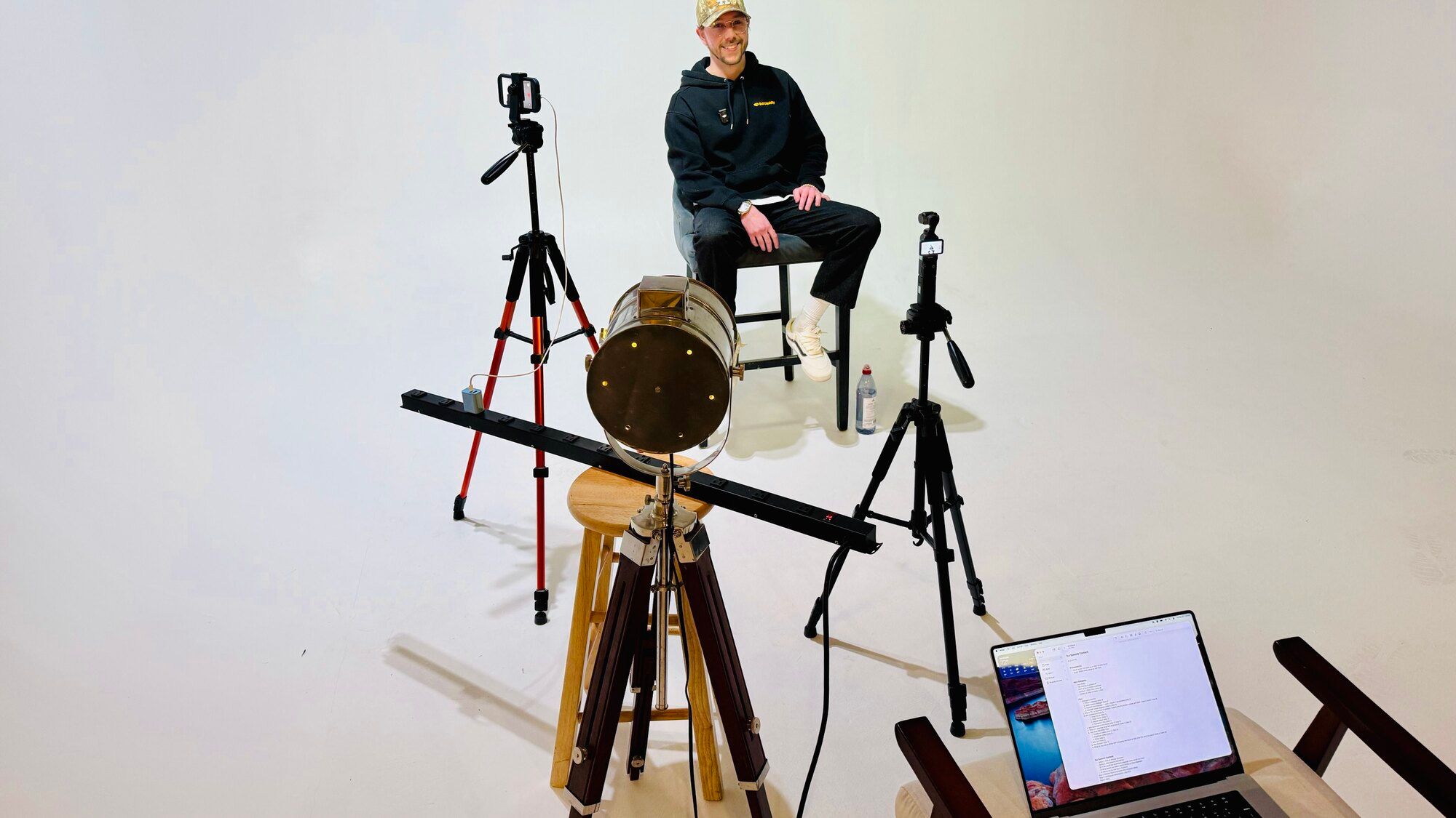 Production room set up for a technical explainer recording, with two cameras on tripods, a key light, a laptop, and the on camera subject seated against a plain backdrop.